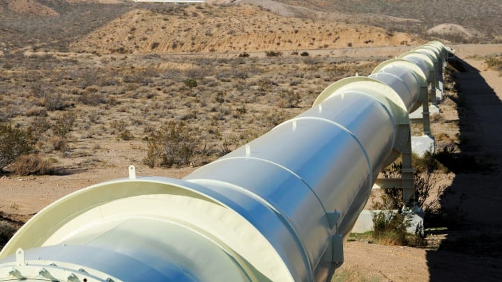 Pipeline in the desert with mountains on the horizan